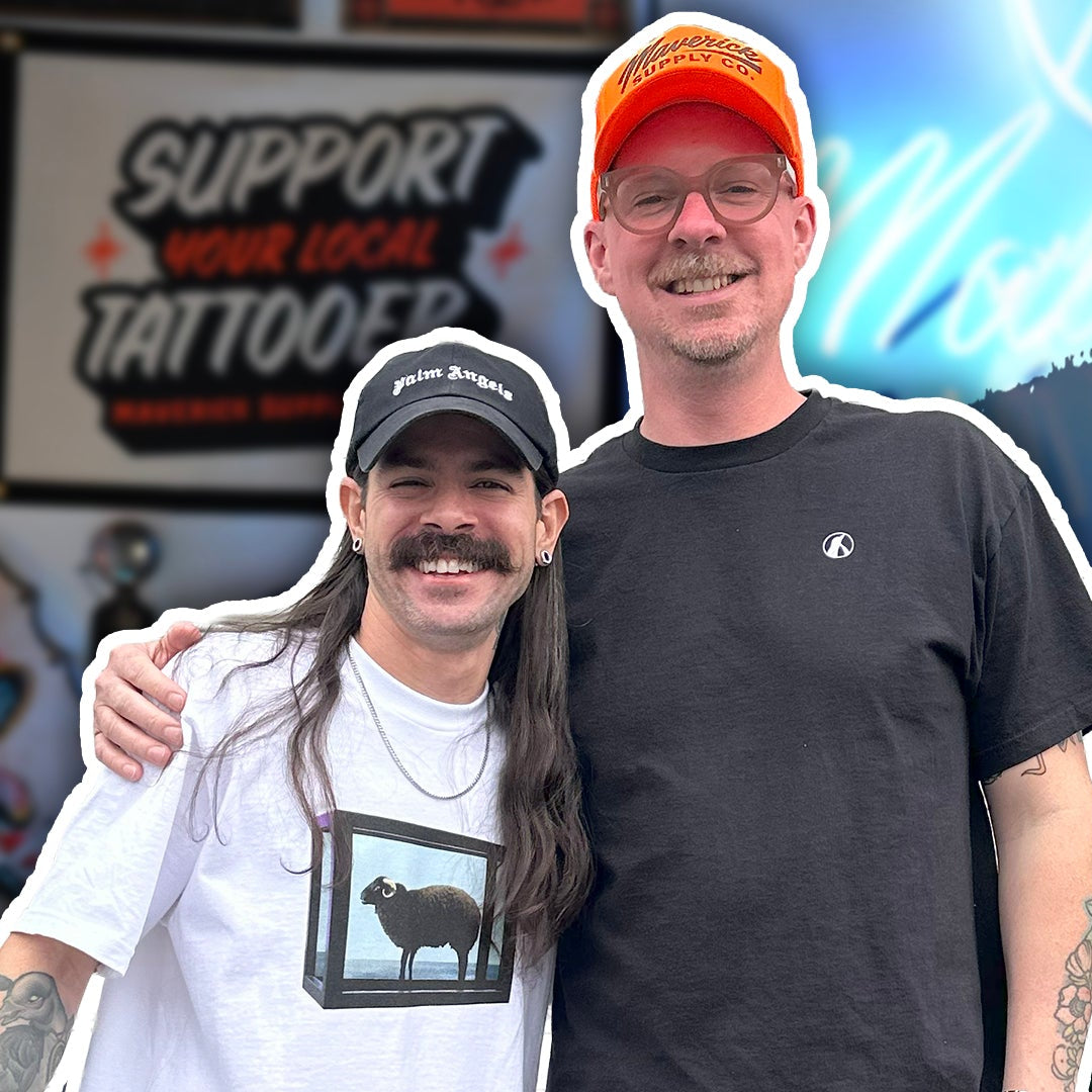Two men standing together with a tattoo shop sign in the background